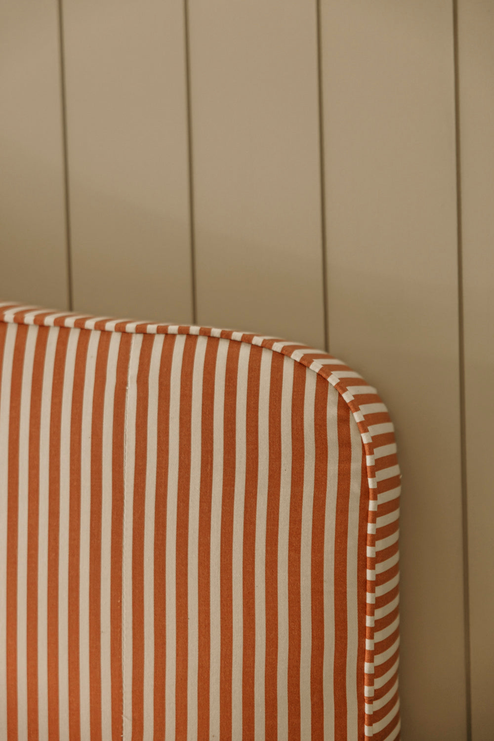 Striped cushion with brown and white pattern against a beige wooden panel background