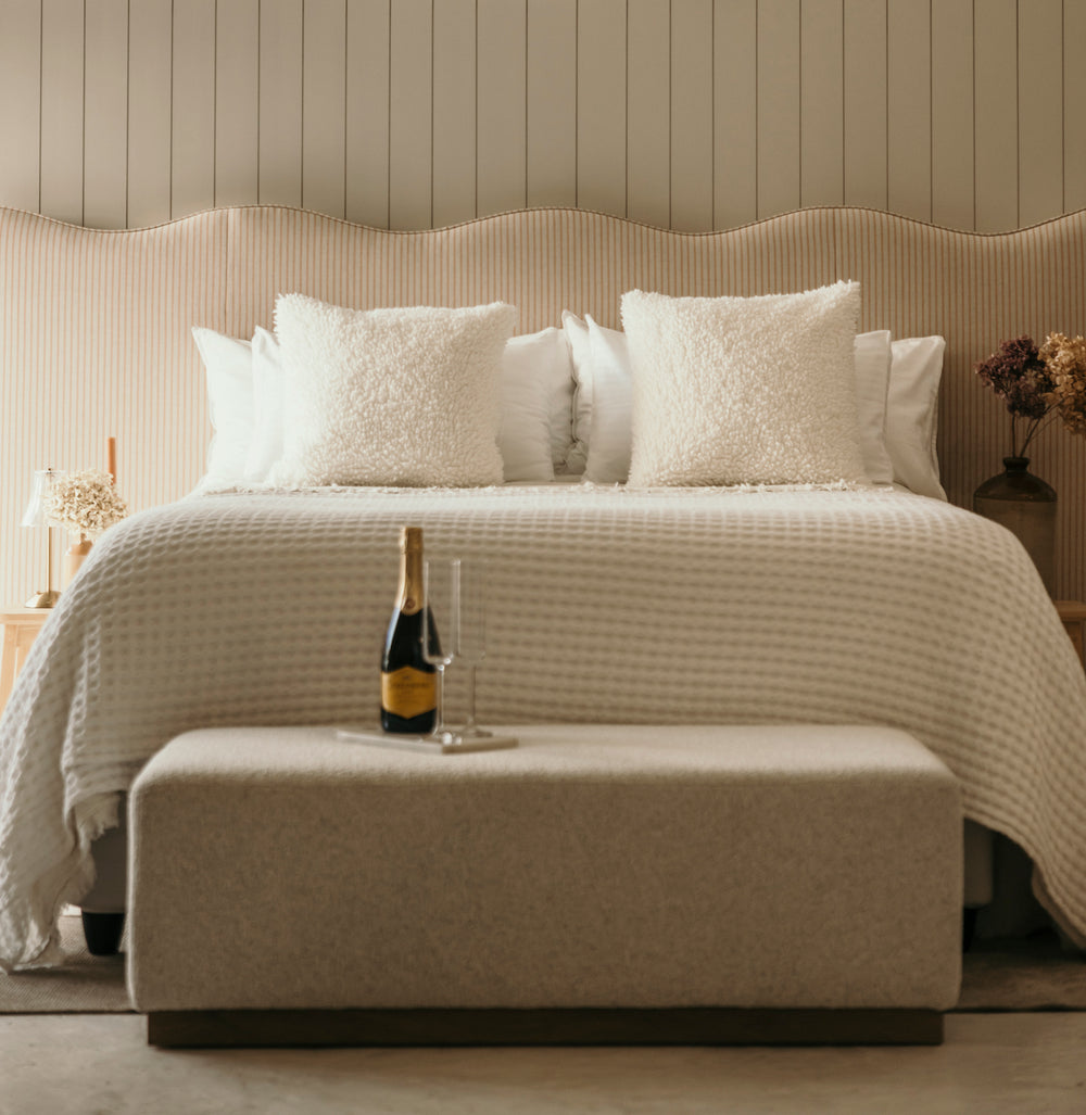 Neatly made bed with white bedding and pillows in a bedroom setting.