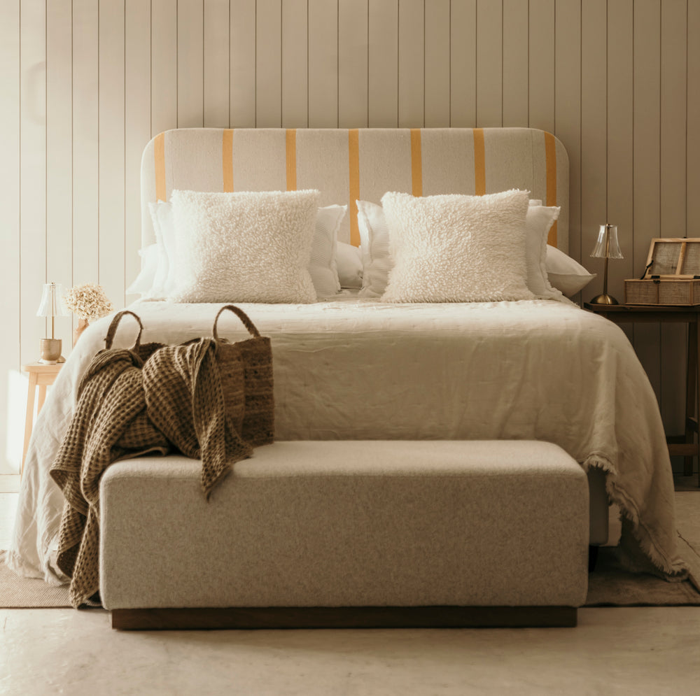 Neatly made bed with striped headboard in a bedroom setting