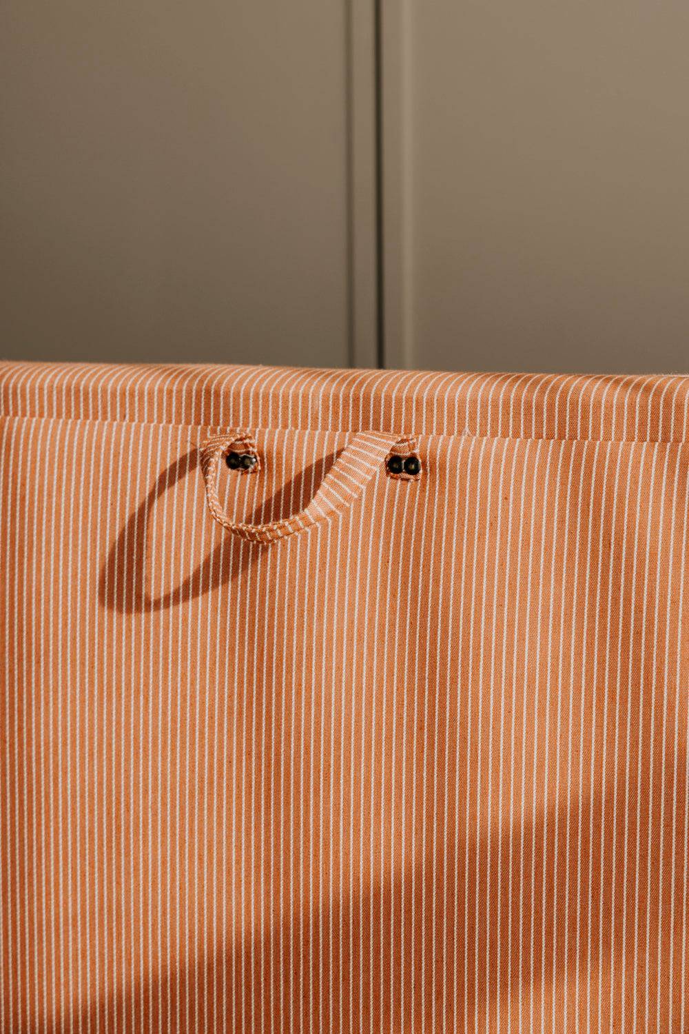 Close-up of a brown striped bag with a handle against a green background
