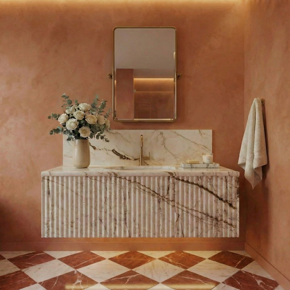 Bathroom interior with a marble vanity, gold mirror, and floral arrangement.