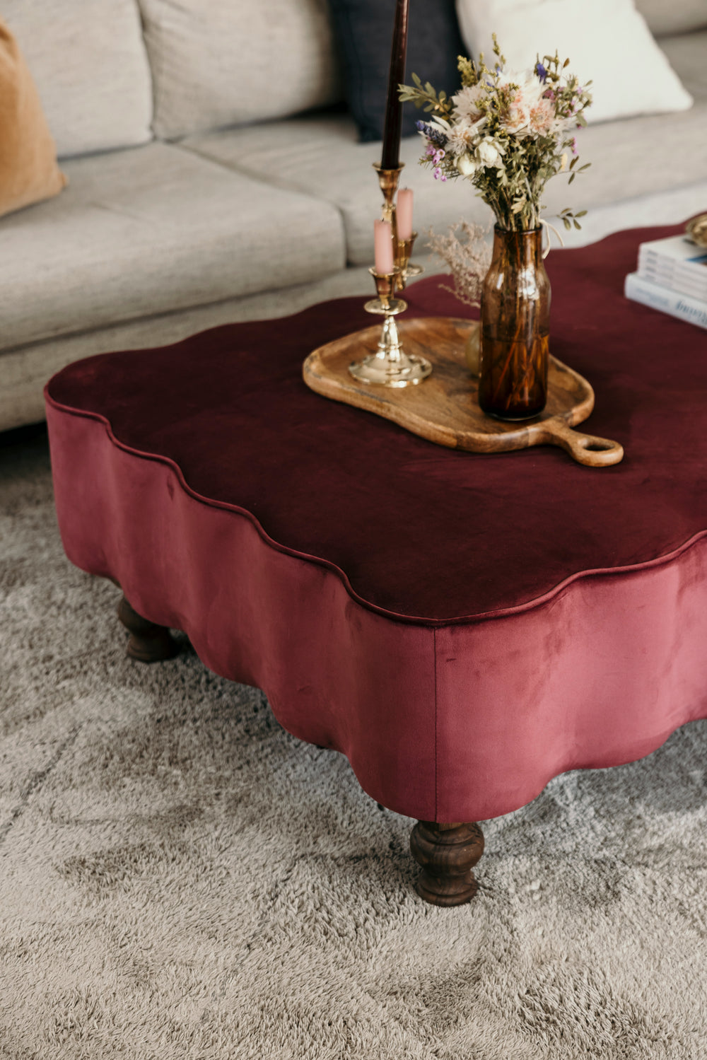 Burgundy velvet coffee table with decorative items on a carpeted floor.