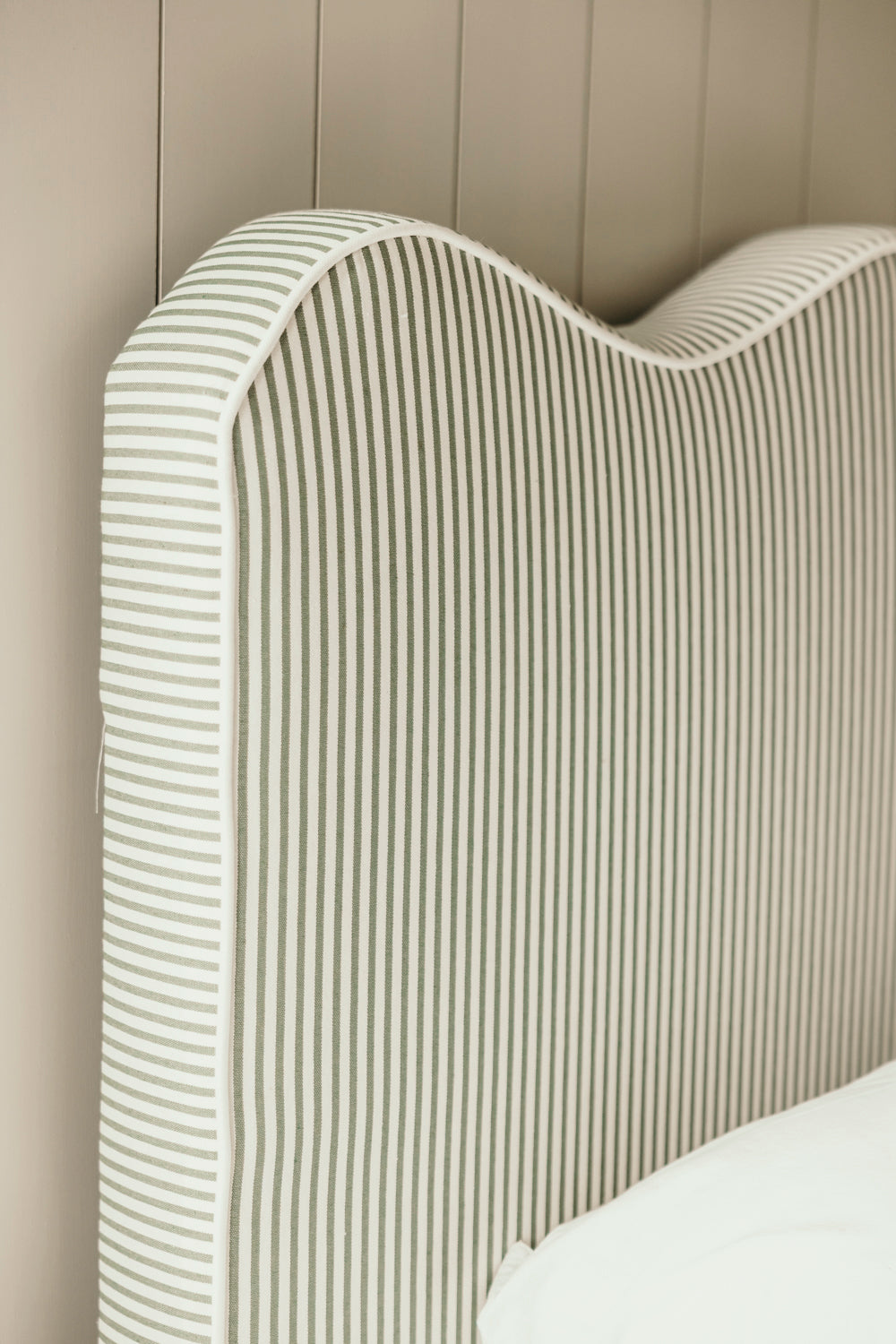 Close-up of a textured headboard against a neutral wall.