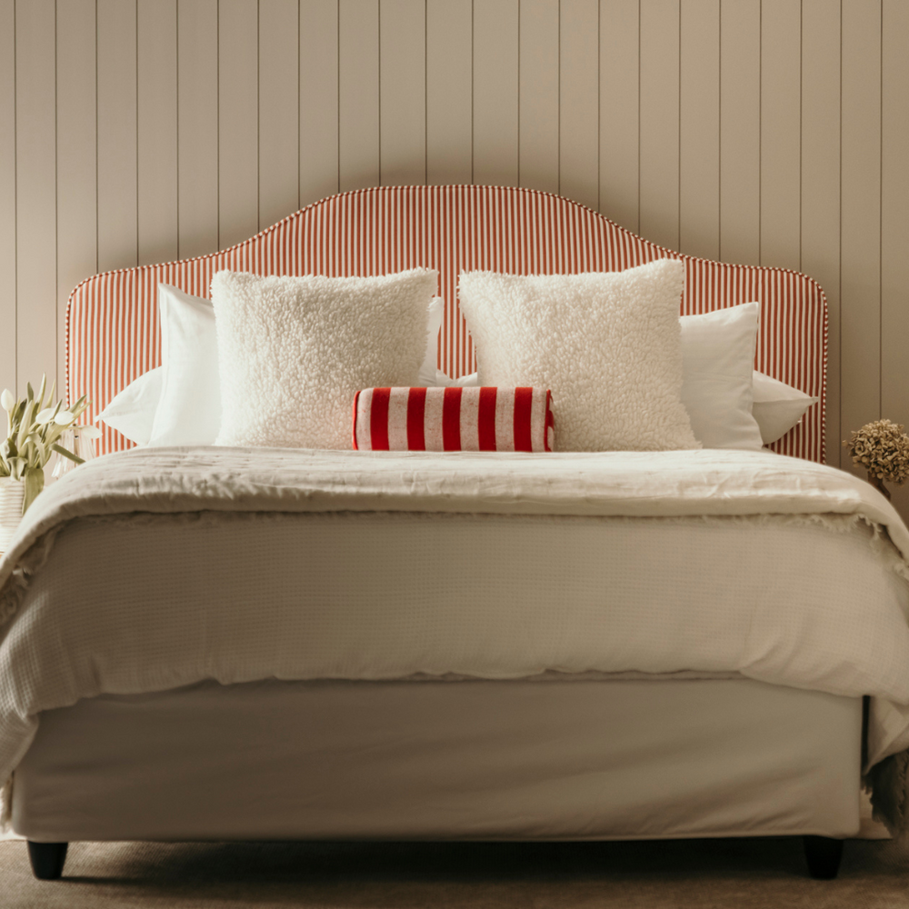Bed with striped headboard and decorative pillows in a bedroom setting