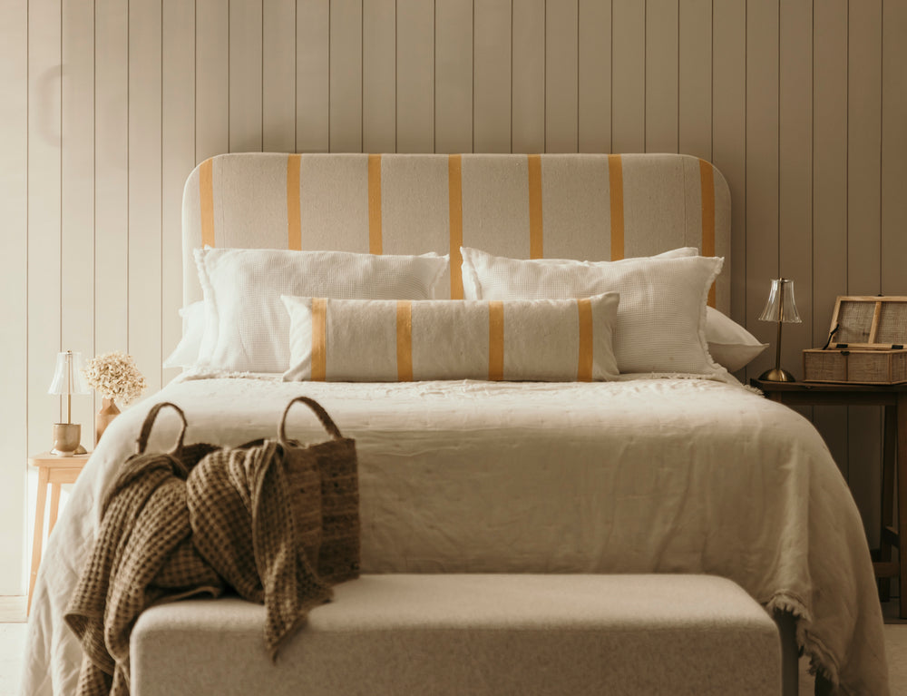 Neatly made bed with striped headboard and pillows in a bedroom setting.
