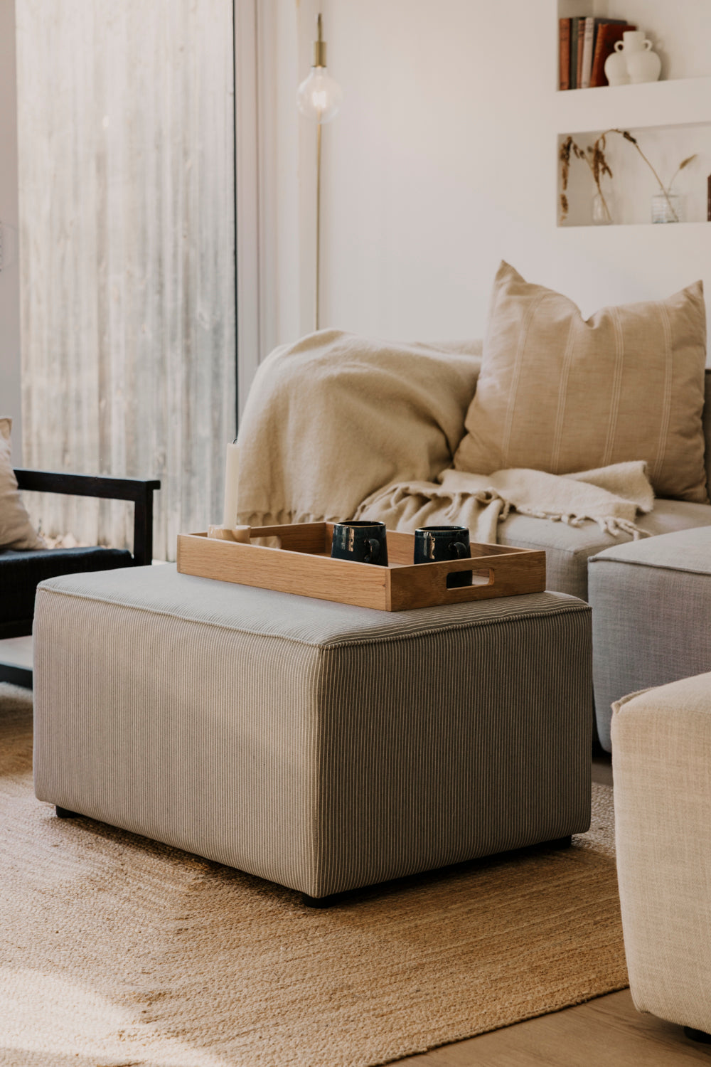 Beige sofa with ottoman and tray in a living room setting