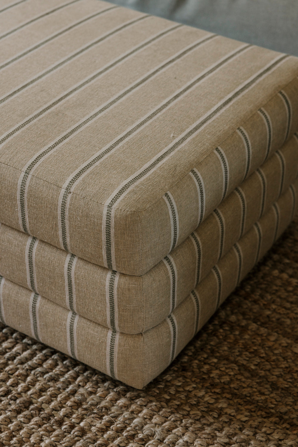 Stack of beige striped mattress toppers on a textured surface