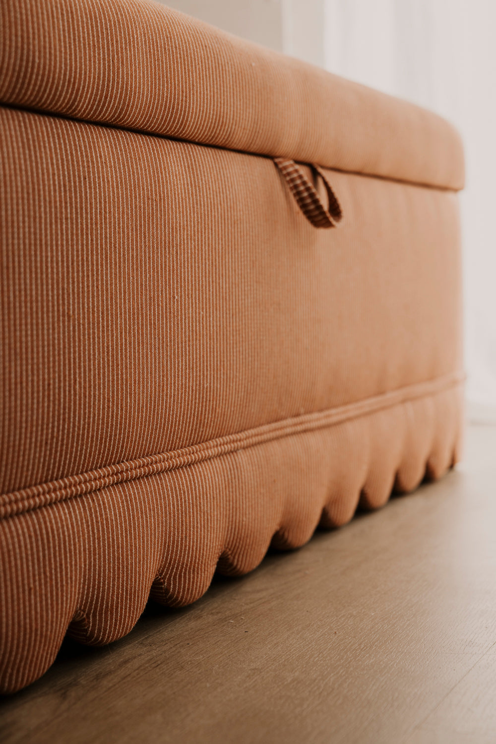 Brown textured ottoman on a wooden floor