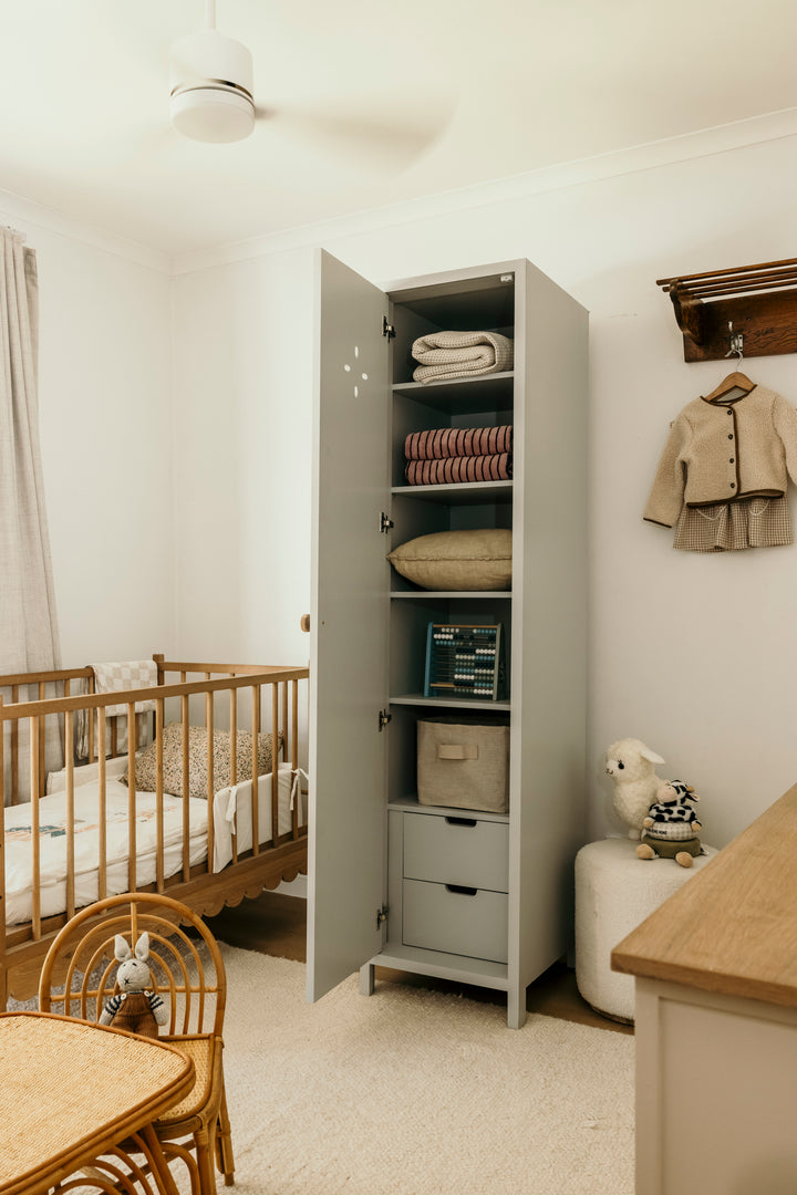 Nursery room with open wardrobe, crib, and baby furniture.