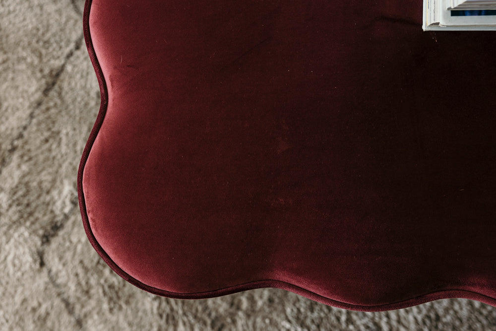 Close-up of a maroon fabric surface on a textured beige background