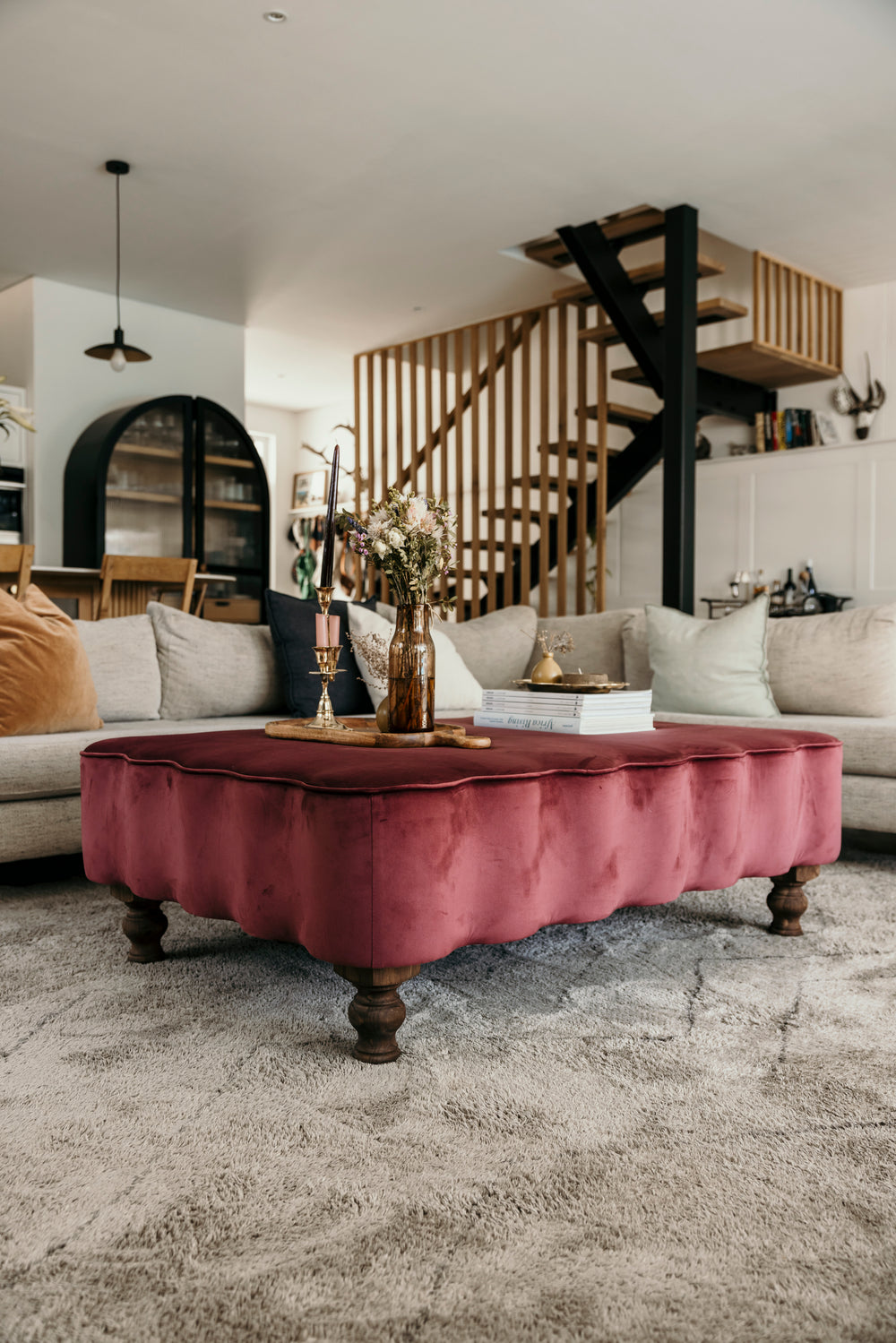 Living room with a pink velvet coffee table and staircase in the background