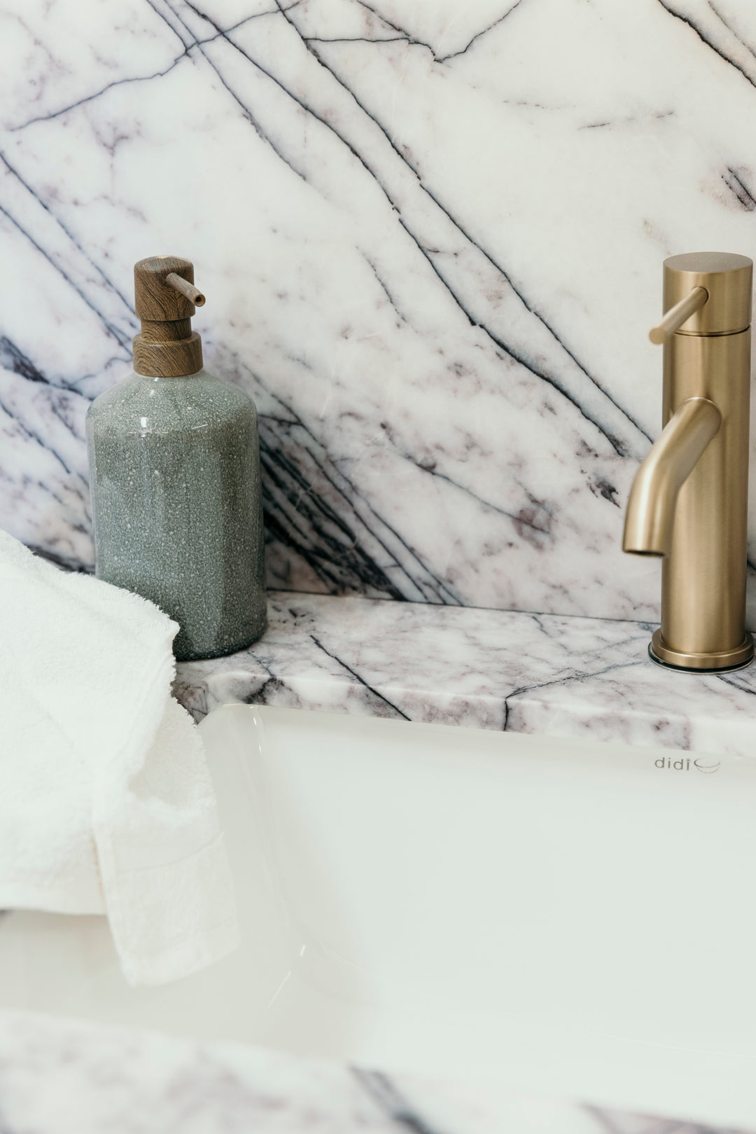 Gold faucet and soap dispenser on a marble countertop