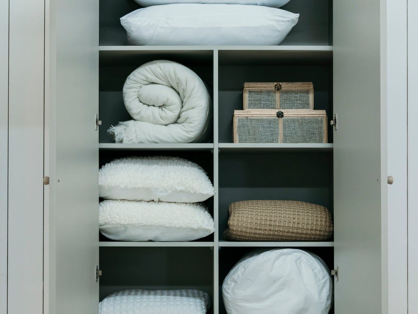 An open bedroom cupboard filled with folded linen